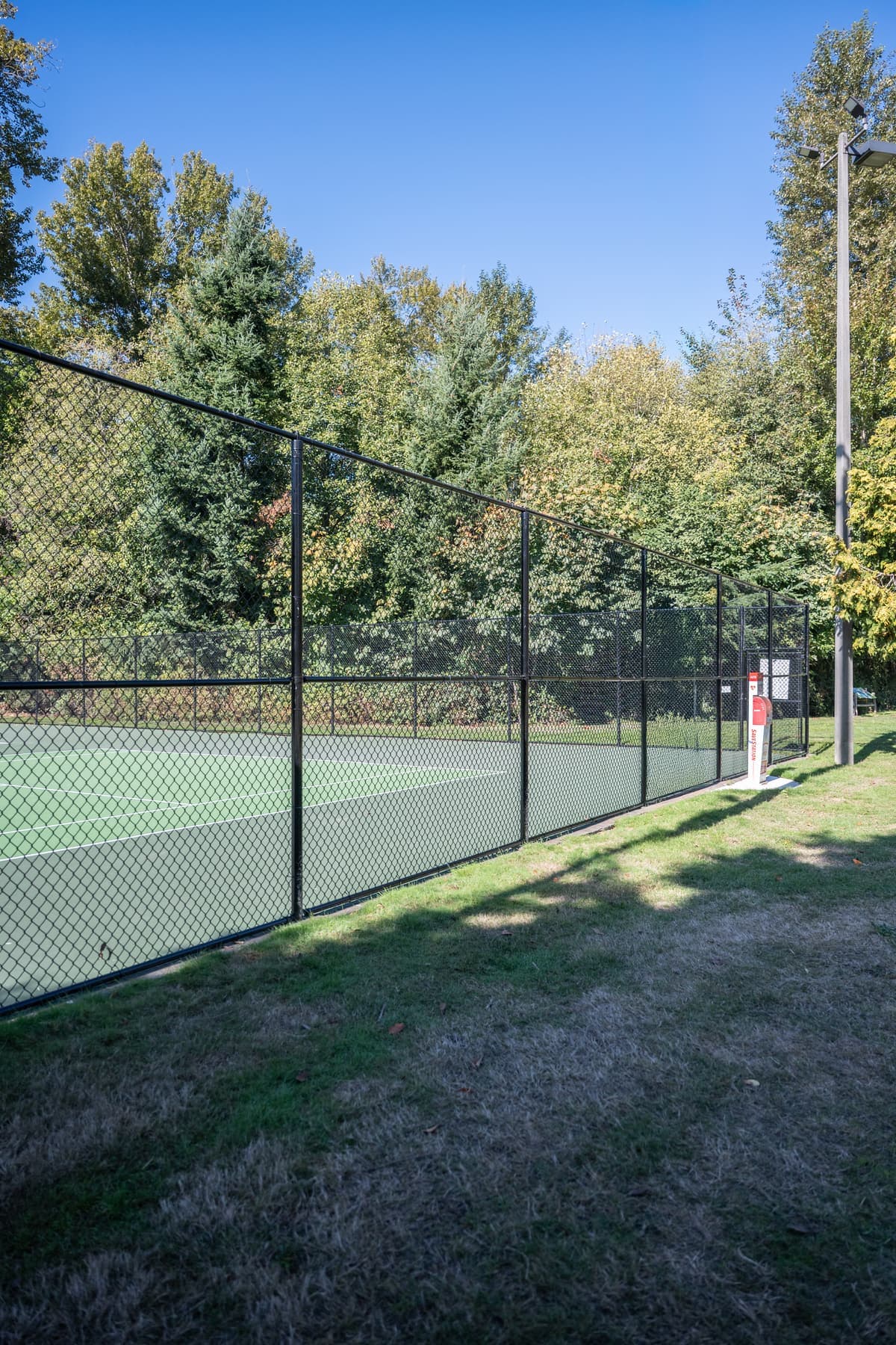 Long run of black chain-link fence along a tennis court